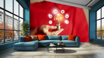 Energy innovation light bulb with future industry of power generation icons graphic interface in woman`s hands. Concept of sustainability development and alternative energy.. Wall mural